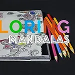 Tegneblok med halvfarvede mandala-designs og farvede blyanter på sort baggrund