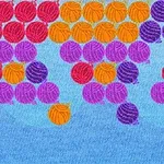 Farverige bånd af garnnøgler i røde, orange, lilla og violette nuancer mod en lyseblå baggrund
