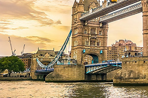 Tower Bridge i London ved solnedgang med vandet i forgrunden og bygninger i baggrunden