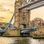Tower Bridge i London ved solnedgang med vandet i forgrunden og bygninger i baggrunden