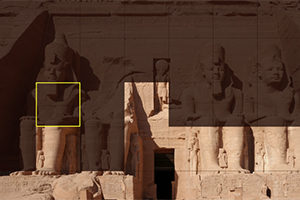 Stenstatuer og gamle egyptiske strukturer indgraveret i klippen i varme sandfarver