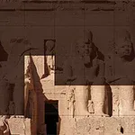 Stenstatuer og gamle egyptiske strukturer indgraveret i klippen i varme sandfarver