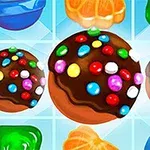 Chokoladebolde med farverige slikperler omgivet af forskellige gelé- og frugtsymboler på en blå baggrund