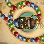 Sort kattefigur omgivet af flerfarvede kugler på en baggrund med egyptiske hieroglyffer